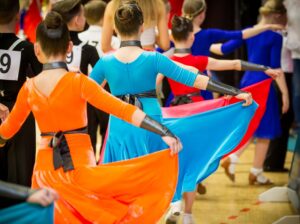 Tyttöjä tanssimassa erivärisissä mekoissa.