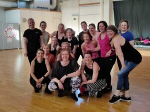 Ryhmä miehiä ja naisia tanssisalilla poseeraamassa kameralle.