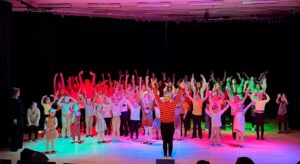 Iso ryhmä ihmisiä vilkuttaa kädet ylhäällä.