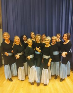 Ryhmä naisia seisoo esiintymisasuissa.