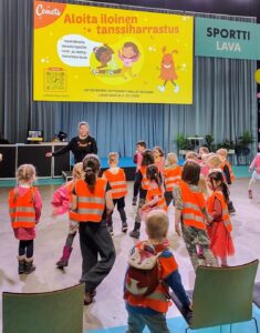 Lapsia huomioliiveissä liikkumassa kohti tanssinohjaaajaa.