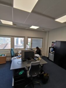 Toimistohuone, jossa yksi  henkilö pöydän ääressä.