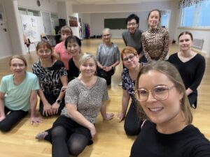 Naisia ja miehiä istuu lattialla.