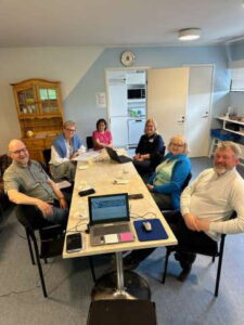 Miehiä ja naisia istuu pöydän ääressä.