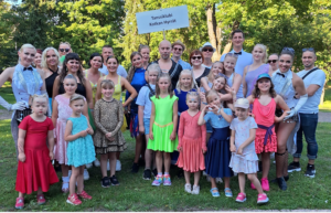 Aikuisia ja lapsia ryhmäkuvassa kesällä, ulkona.