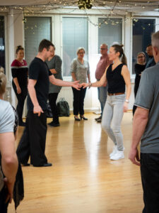 Valmentajapari näyttämässä opeteltavaa asiaa ryhmän keskellä.