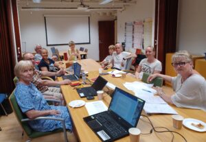 Pöydän ääressä kokouksessa istuvia ihmisiä, jotka katsovat kameraan.