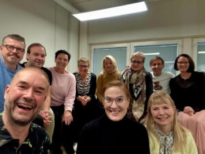 Hymyileviä miehiä ja naisia ryhmäkuvassa.