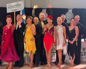 Rivissä eri ikäisiä tanssijoita kilpailuasuissa.